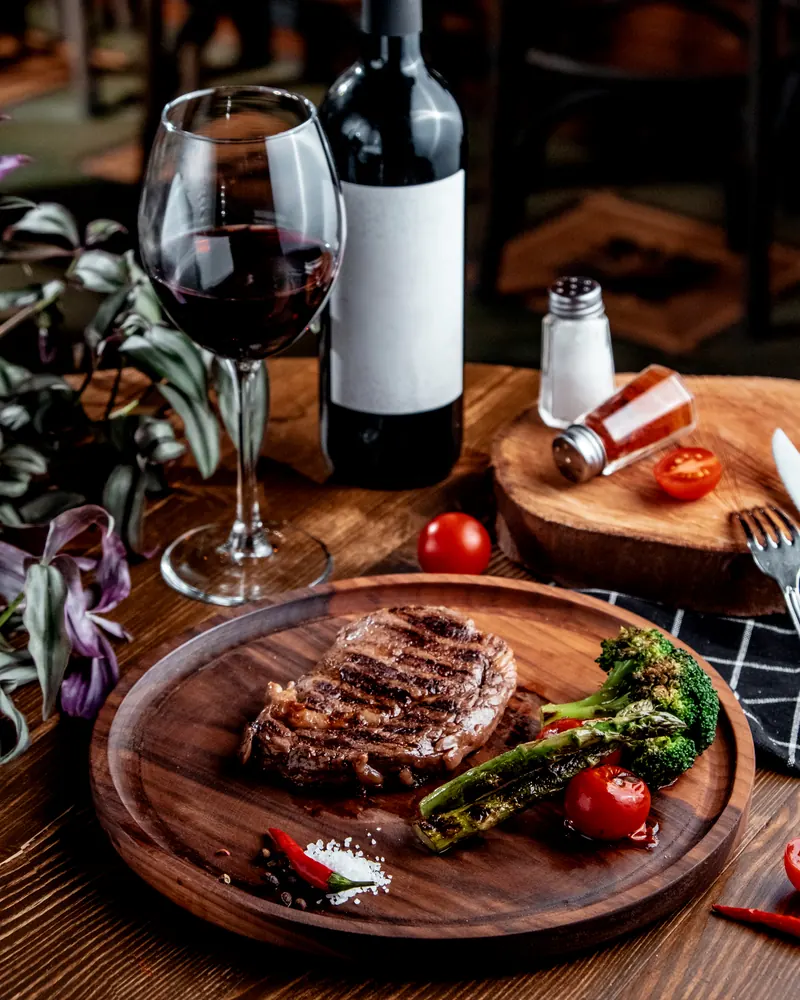 Corte grelhado servido com legumes na brasa e vinho