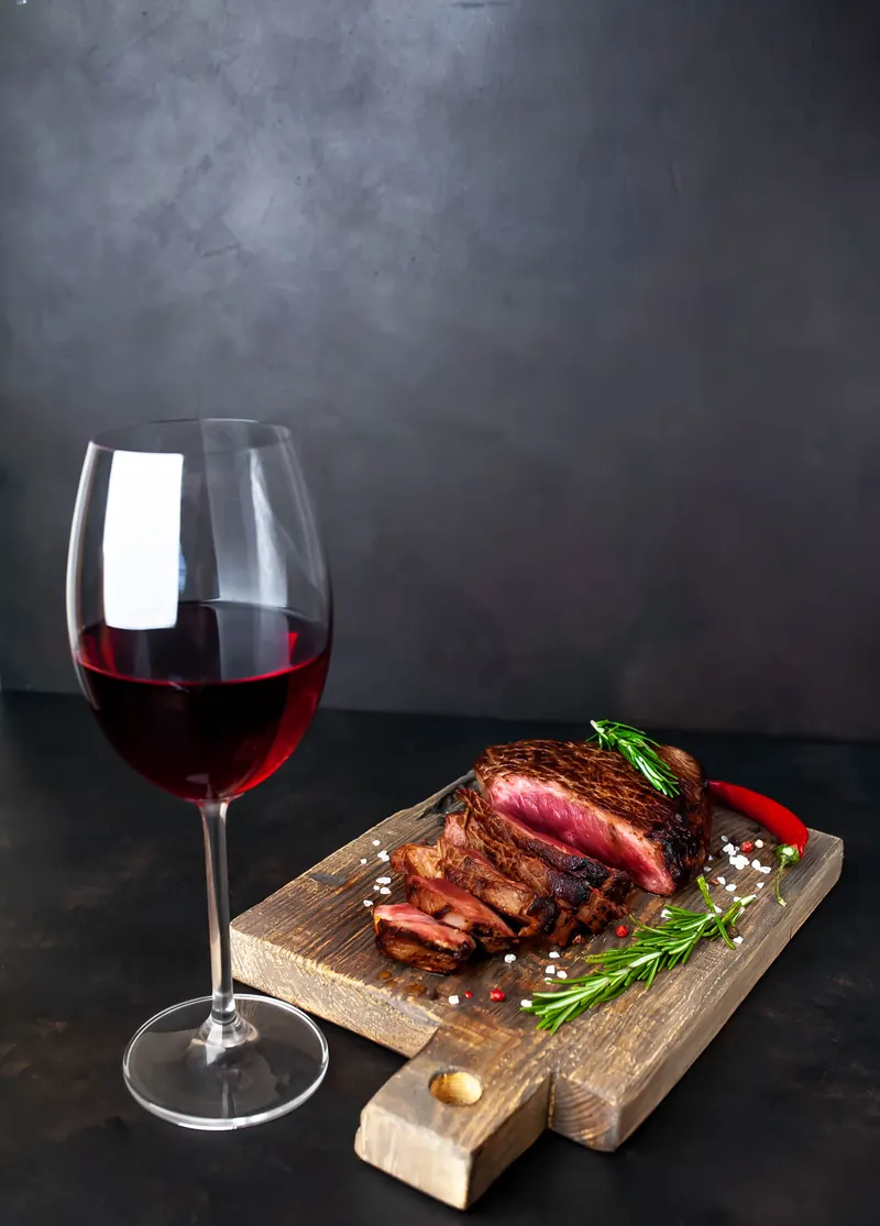 Taça de vinho tinto ao lado de corte fatiado